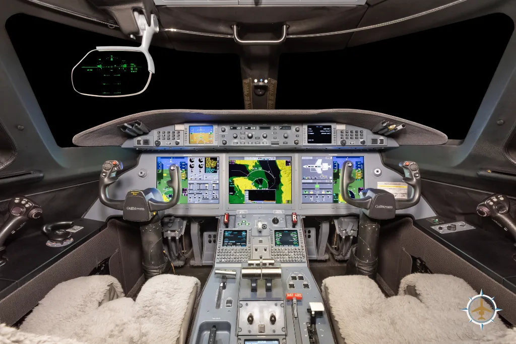 The cockpit of a modern business jet with multiple digital displays and control yokes.