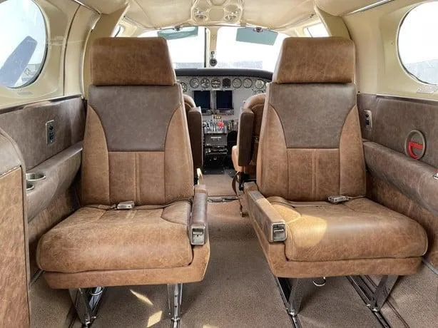 View from the aircraft cabin showing brown and tan leather seats in the foreground and the cockpit instrument panel in the background.