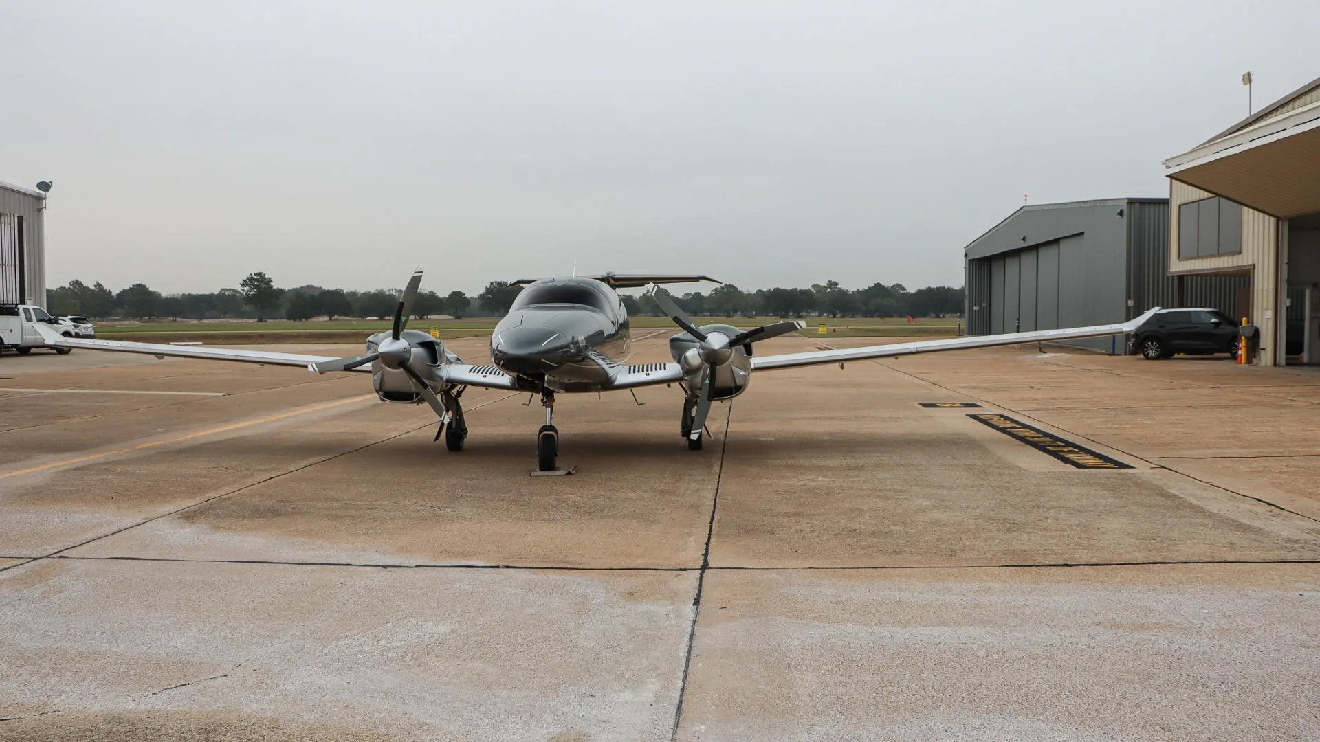A front view of the gray and silver Diamond DA62 aircraft, N502LA, parked on an airport tarmac.