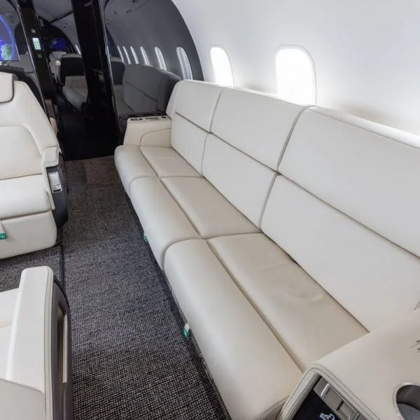 A close-up view of the cream leather sofa with detailed stitching in the private jet cabin.