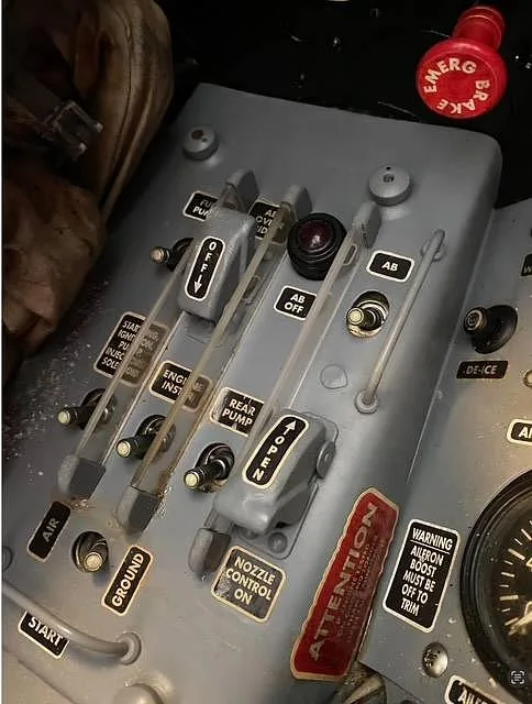 A close-up of the side control panel in a vintage jet cockpit, showing various switches and levers.