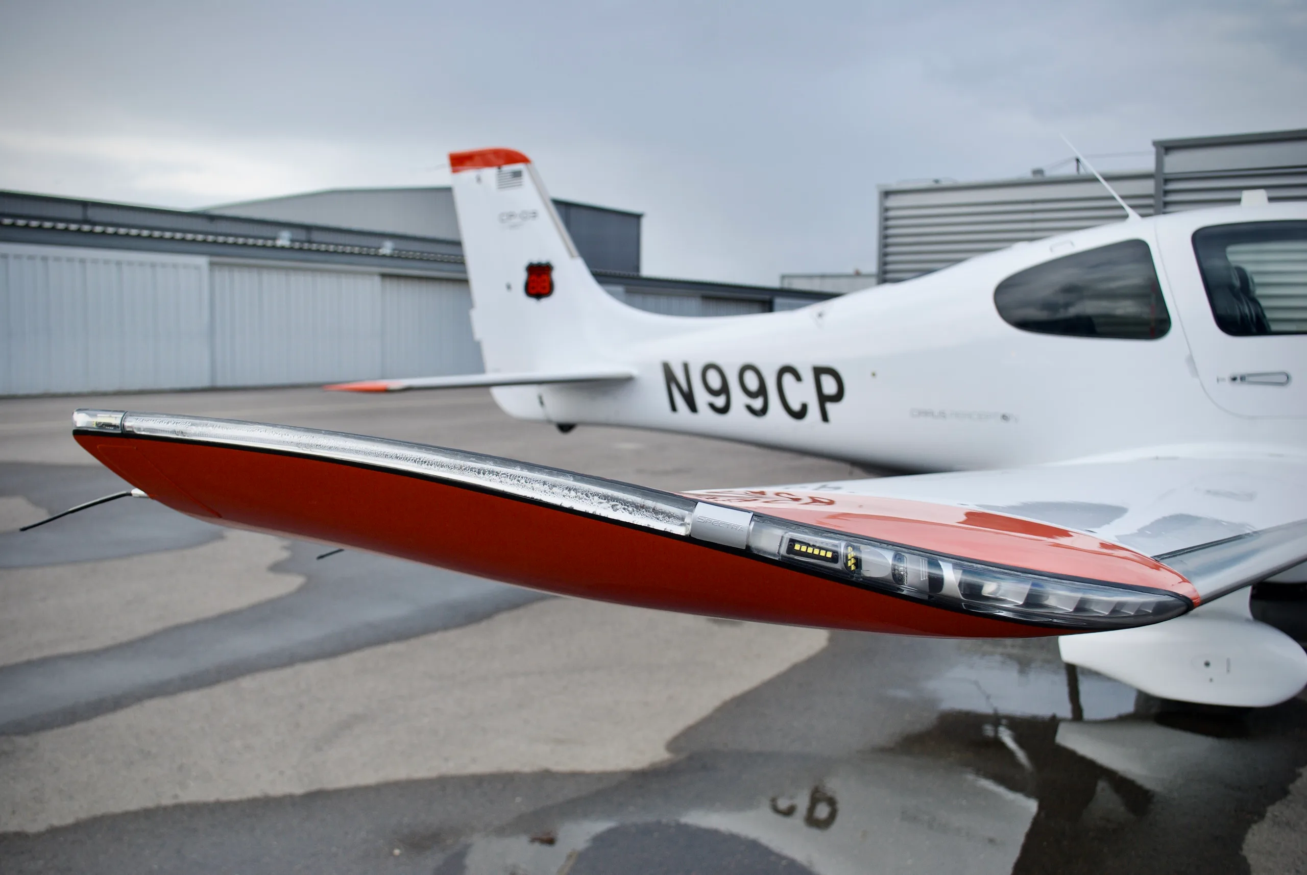 A close-up view of the orange-tipped winglet of the Cirrus SR22T aircraft N99CP, showing integrated lights.