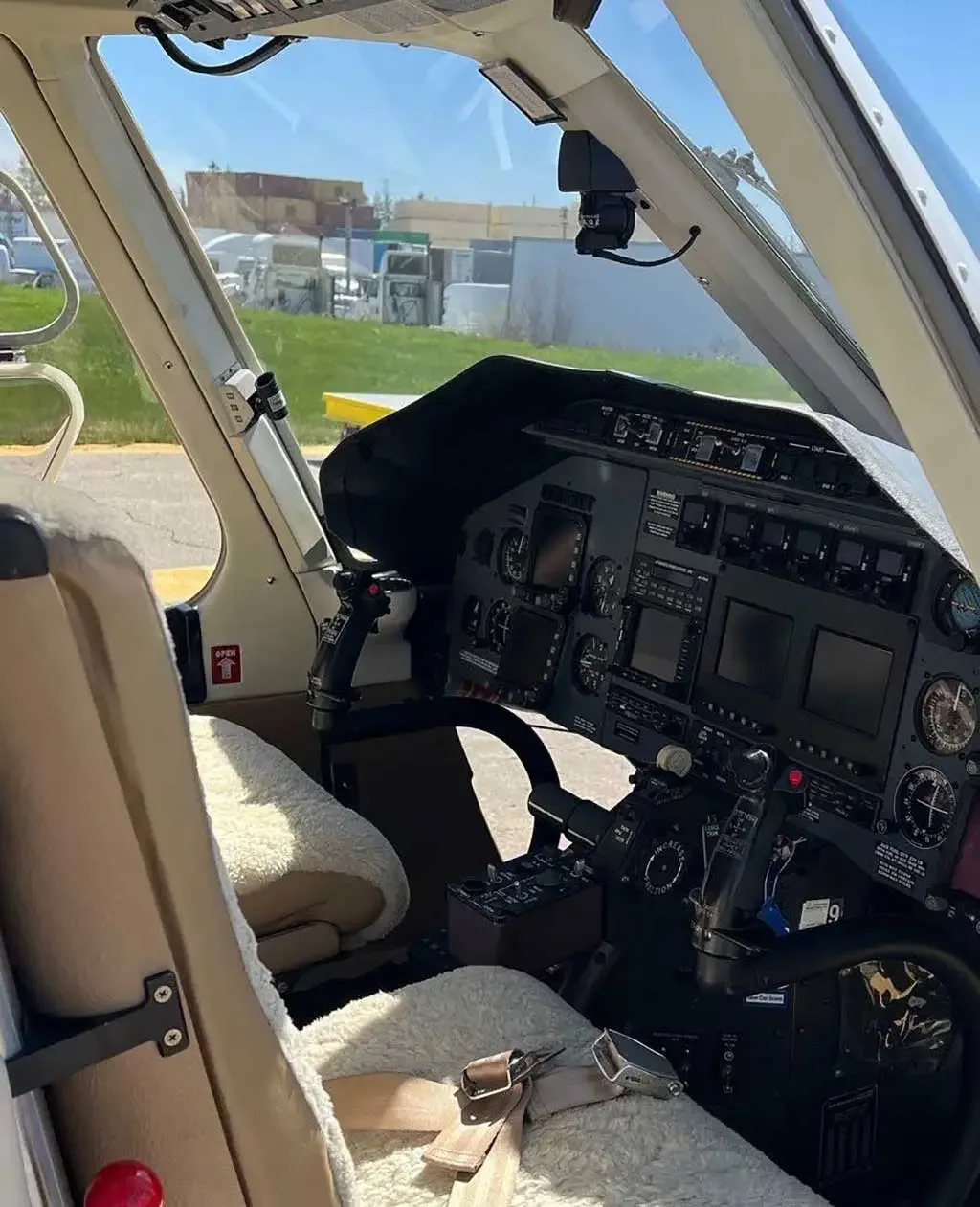 The cockpit of a helicopter features a detailed instrument panel, controls, and a sheepskin-covered pilot's seat.