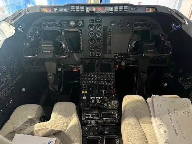 The detailed cockpit of a business jet, featuring multiple screens, instruments, and two control yokes.