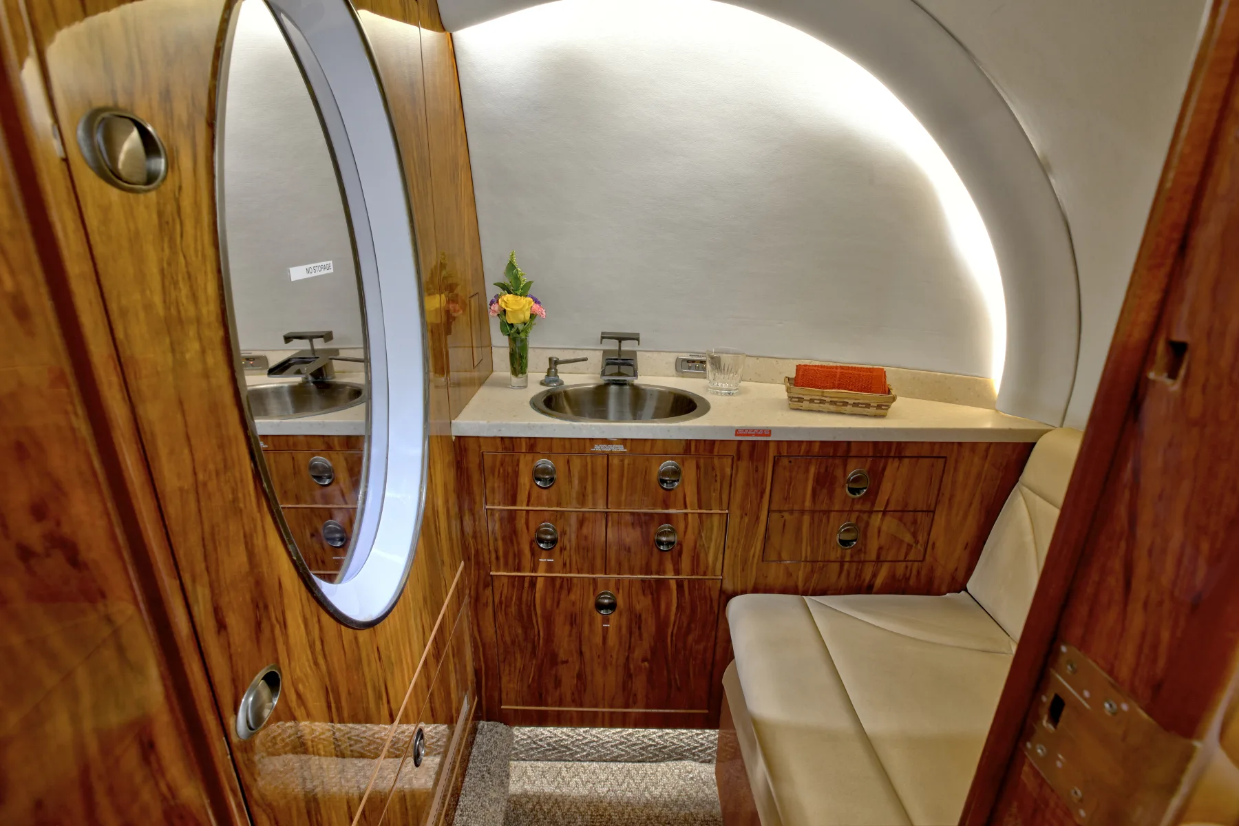 A lavatory with wood cabinets and a sink inside the aircraft.