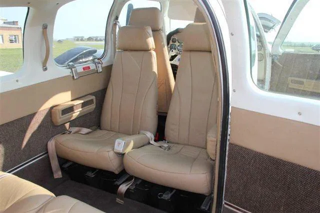 The tan leather passenger seats in the rear cabin of a small aircraft, viewed from the open door.