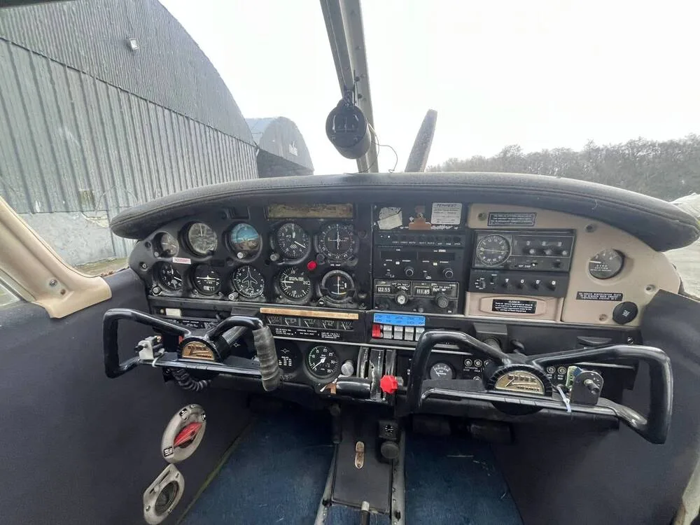 The cockpit of the Piper Cherokee 140 (N228WF) showing the instrument panel, yokes, and controls.
