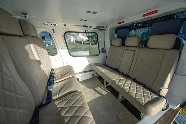 The spacious interior of a helicopter cabin features light brown quilted leather seats.