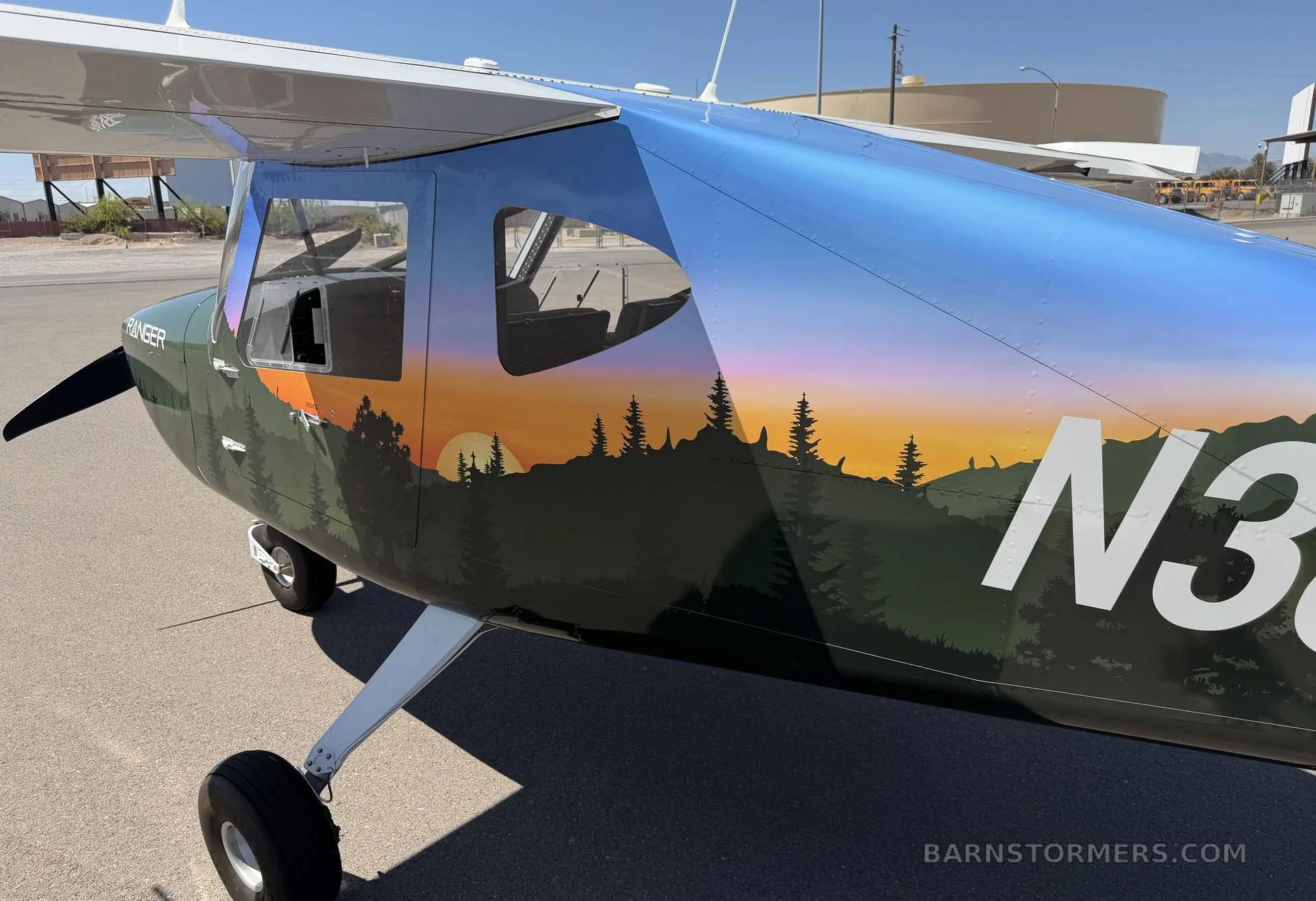 A close-up view of the right fuselage of a 'Ranger' light-sport aircraft, showing its forest and sunset paint scheme and registration N382VR.