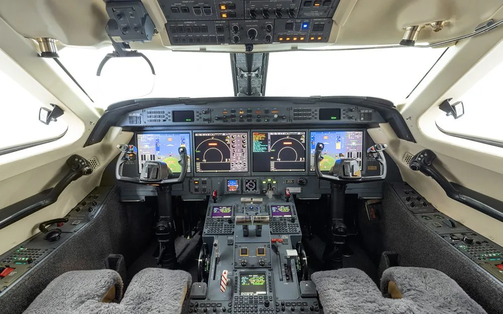 The cockpit of a Gulfstream G550, showing multiple digital displays and control panels.