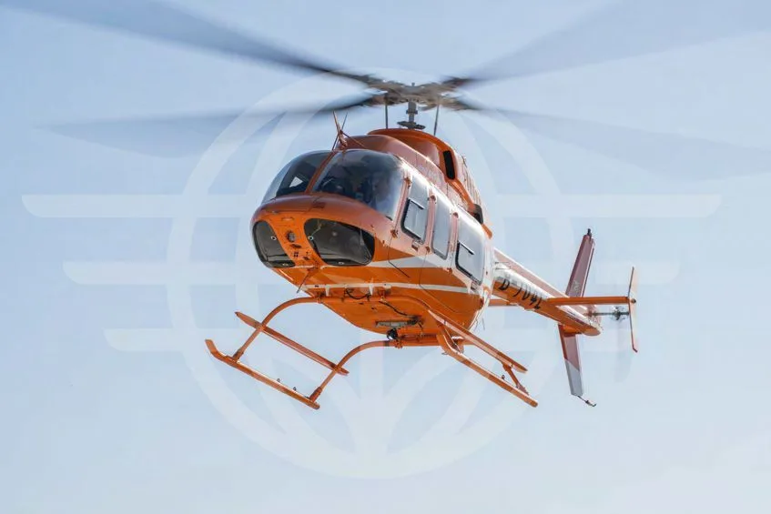 An orange Bell 407EXP helicopter with registration B-704L flies against a clear blue sky, viewed from below and slightly to the front.