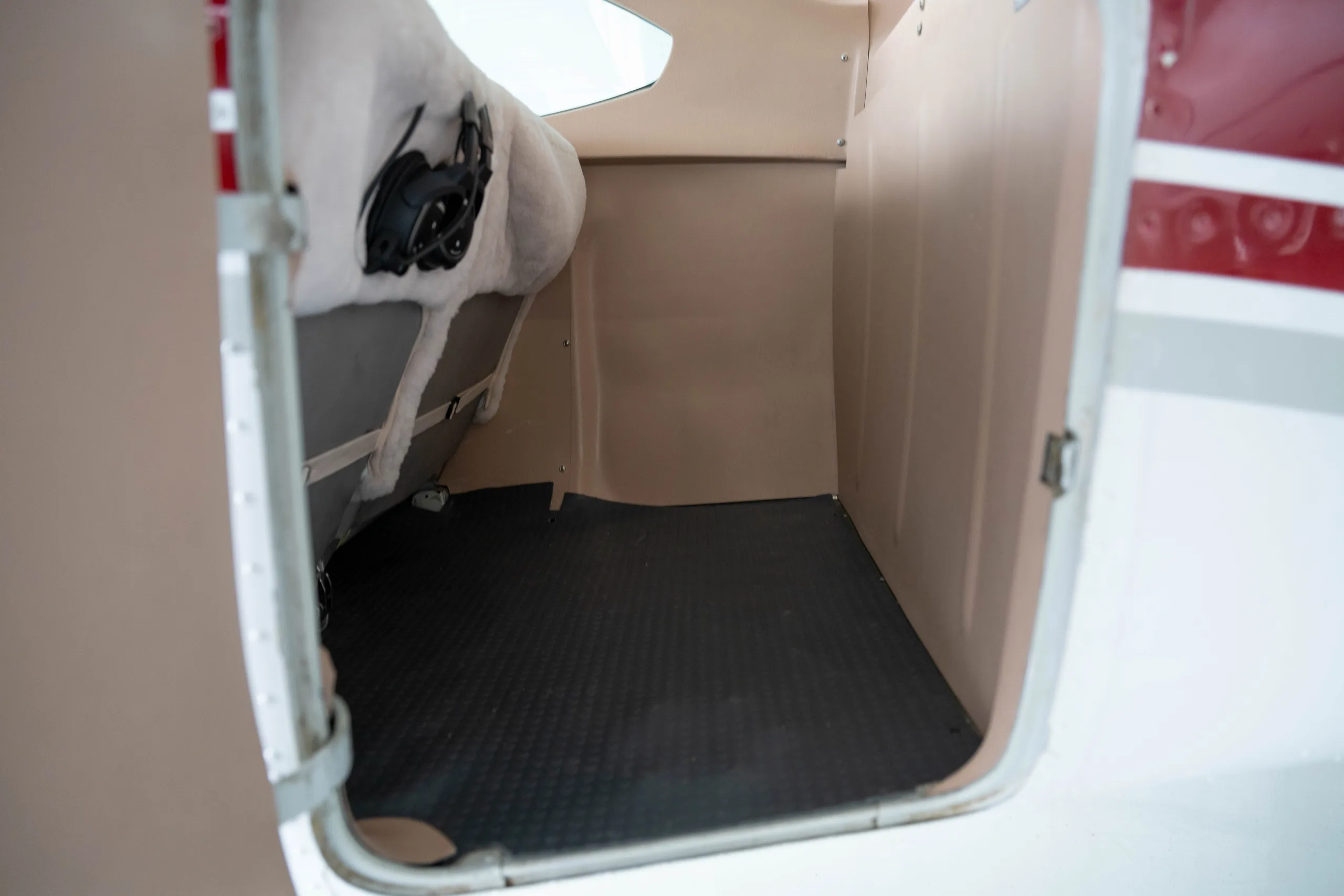 The open cargo compartment of a small aircraft with a black rubber mat.