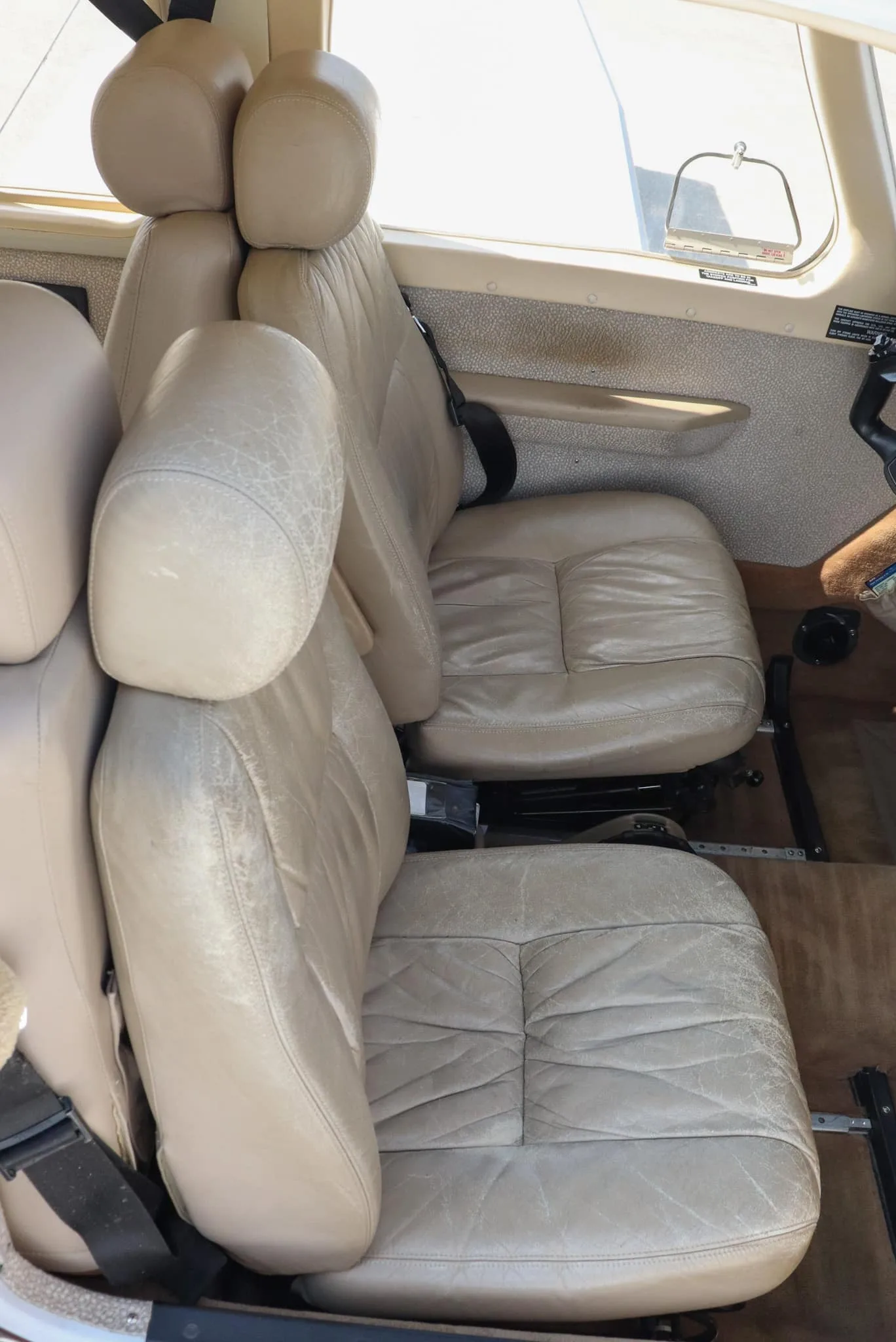 Two light brown leather cabin seats with some wear, viewed from the side.