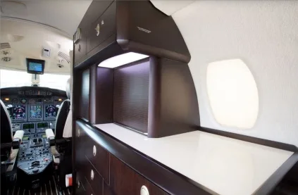 A view from the cabin shows a dark wood cabinet and counter area, with the cockpit visible in the background.