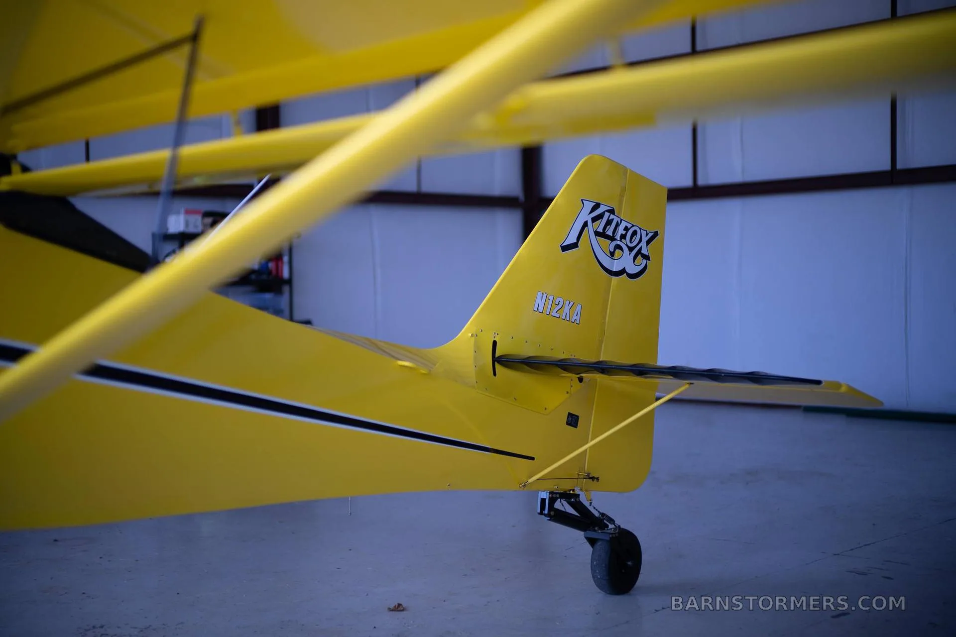 A close-up view of the yellow Kitfox aircraft's tail with the "Kitfox" logo and registration N12KA.