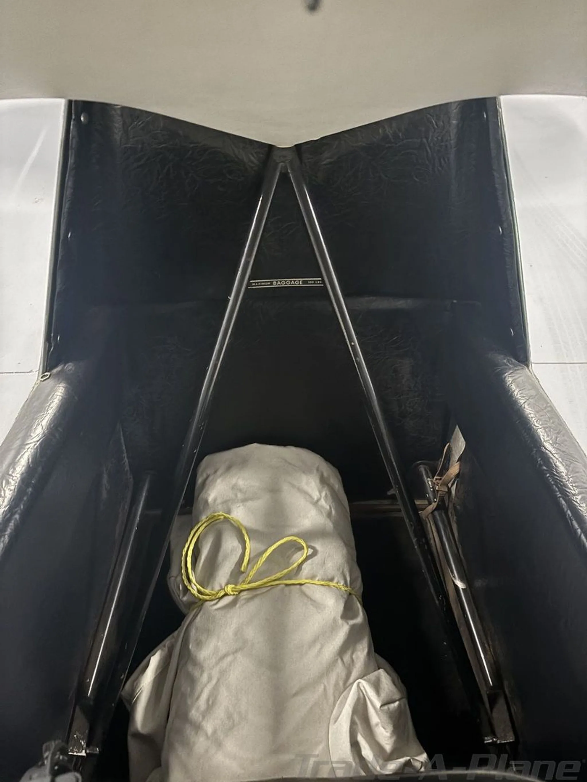 The rear cabin or baggage area of the aircraft, with a white covered item secured by a yellow rope.