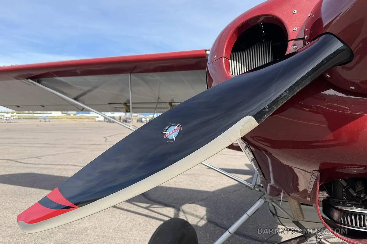 A close-up view of the black propeller and red engine cowling of the aircraft.