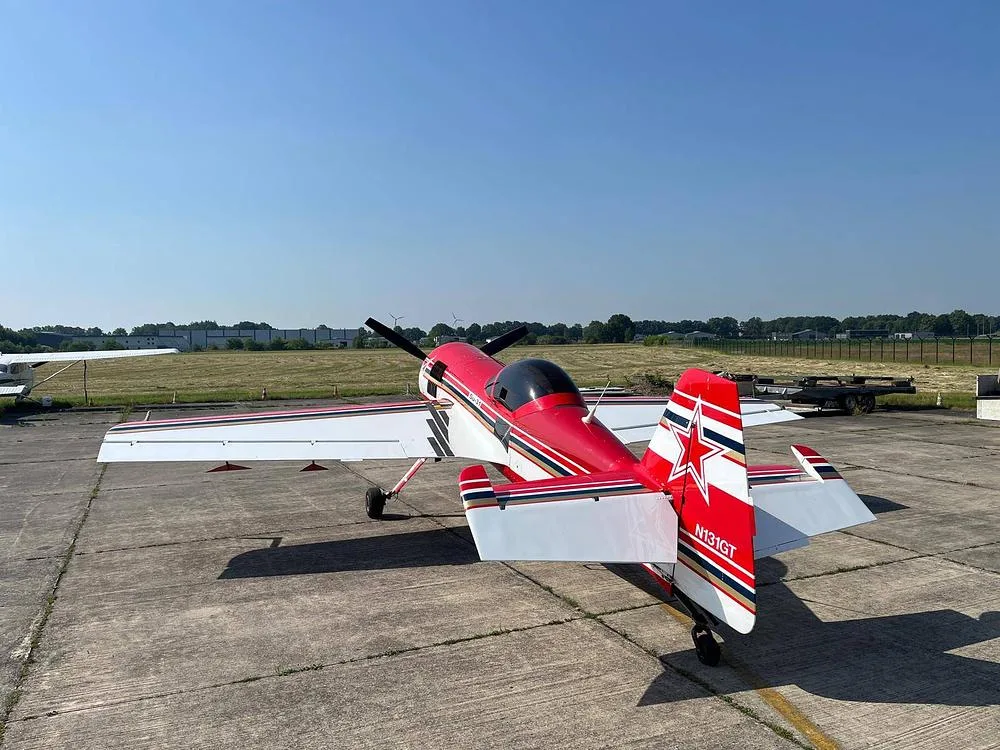 A red and white Sukhoi Su-31 aerobatic aircraft with registration N131GT is parked on a concrete tarmac, viewed from the rear-right.
