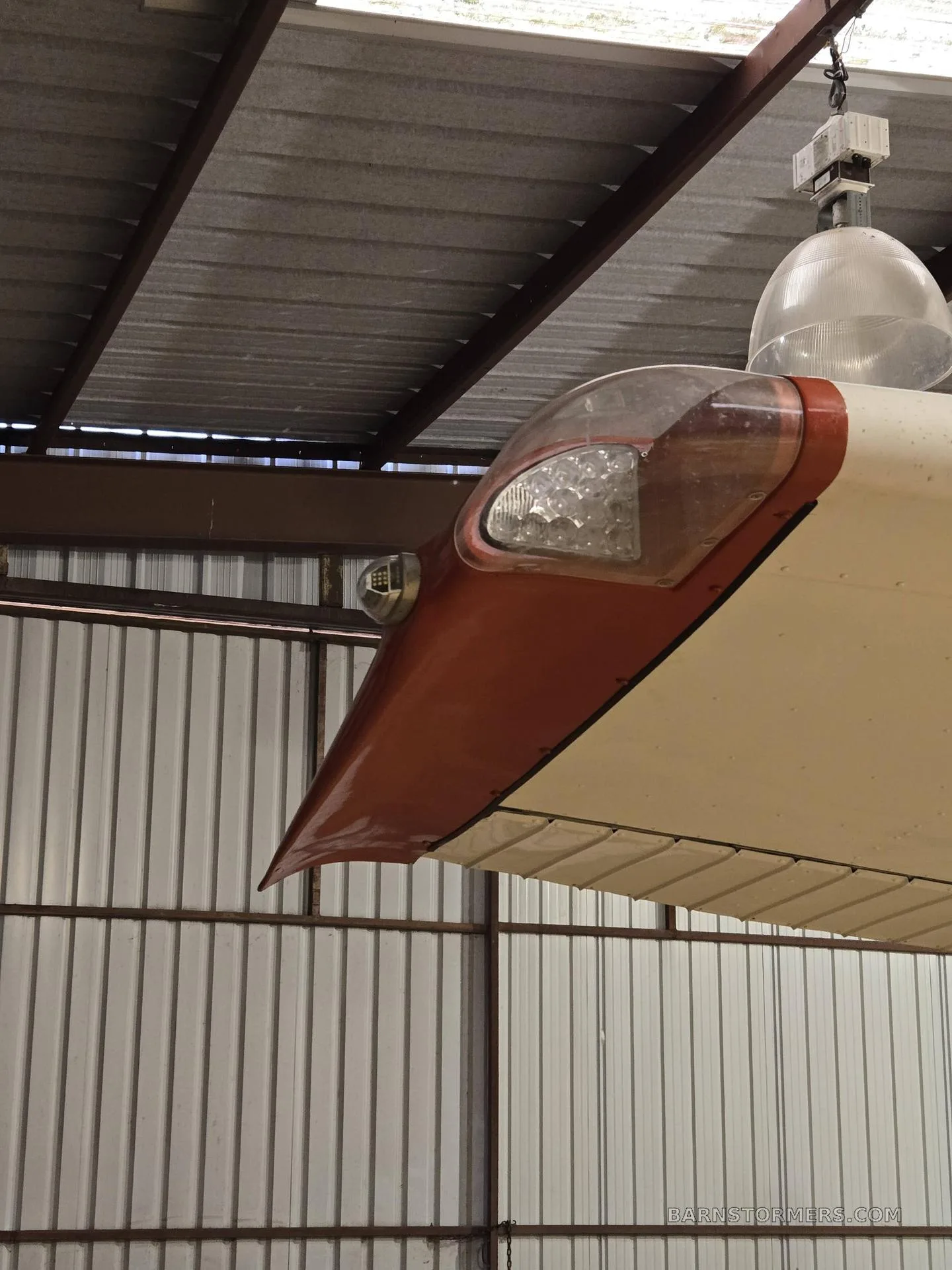A close-up view of the wingtip of the red and white aircraft, featuring the navigation light.