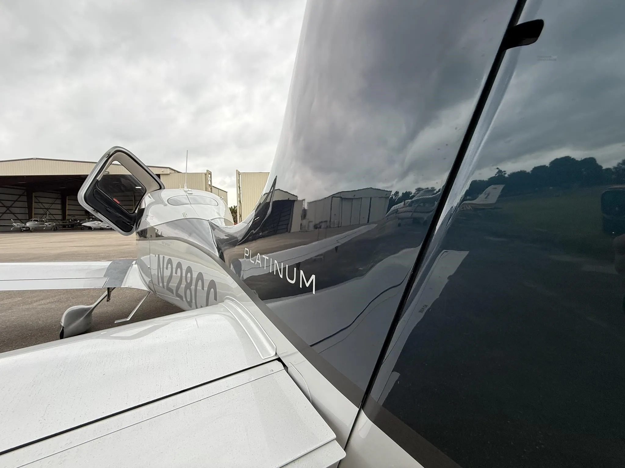 A close-up view of the tail of the N228CC Cirrus SR22T with an open door, showing the "PLATINUM" designation and reflections.