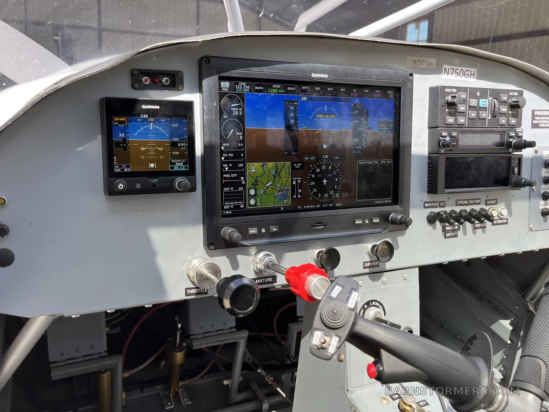 The cockpit of an aircraft featuring Garmin glass panel displays and a joystick control.