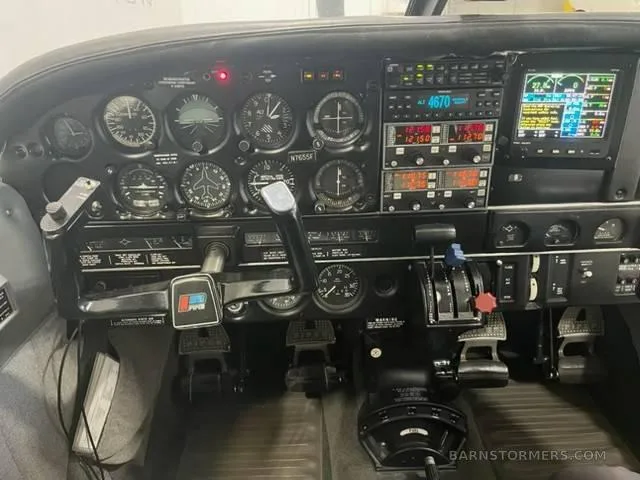 The cockpit instrument panel of a small aircraft, featuring analog gauges and a modern digital display.