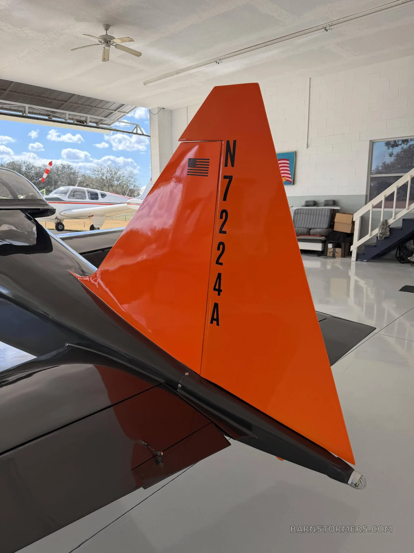 A close-up of the bright orange vertical stabilizer of the aircraft, showing the tail number N7224A and an American flag decal.