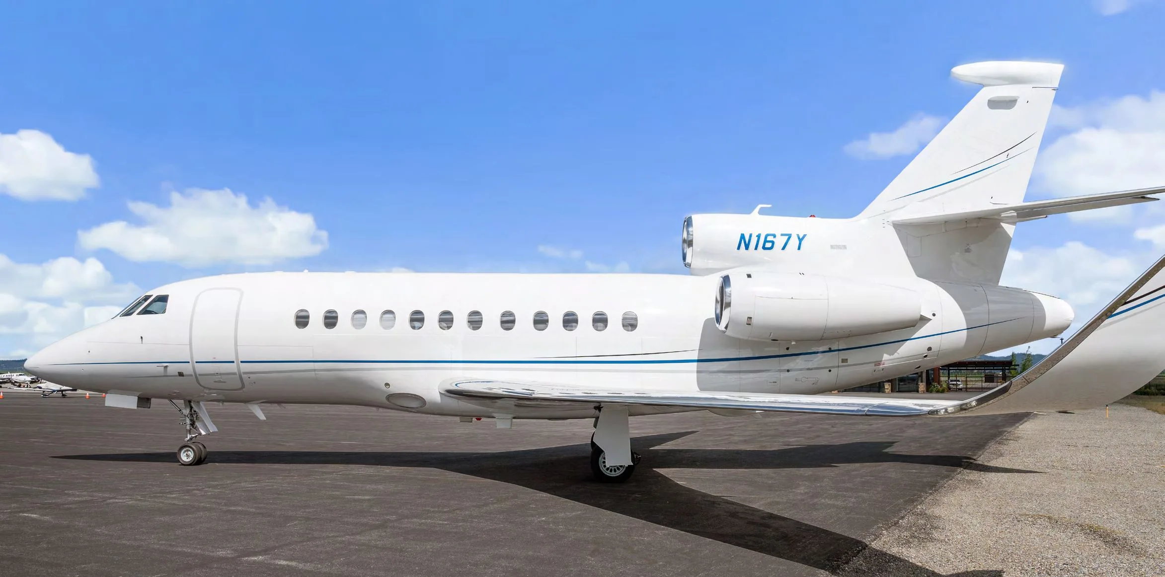 A three-quarter front view of a white Dassault Falcon 900EX business jet, registration N167Y, on an airfield.