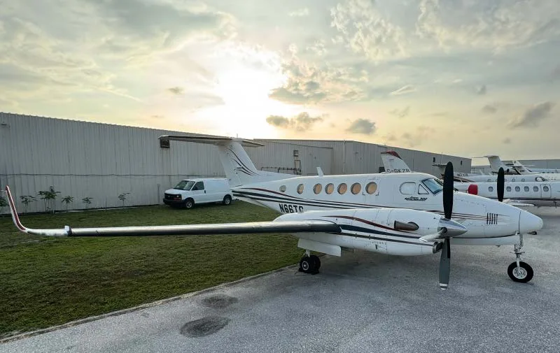 A King Air 200 aircraft with registration N66TG parked on the tarmac at sunset.