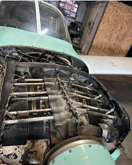 The exposed engine of a Piper Cherokee Six aircraft, showing cylinders and mechanical components.