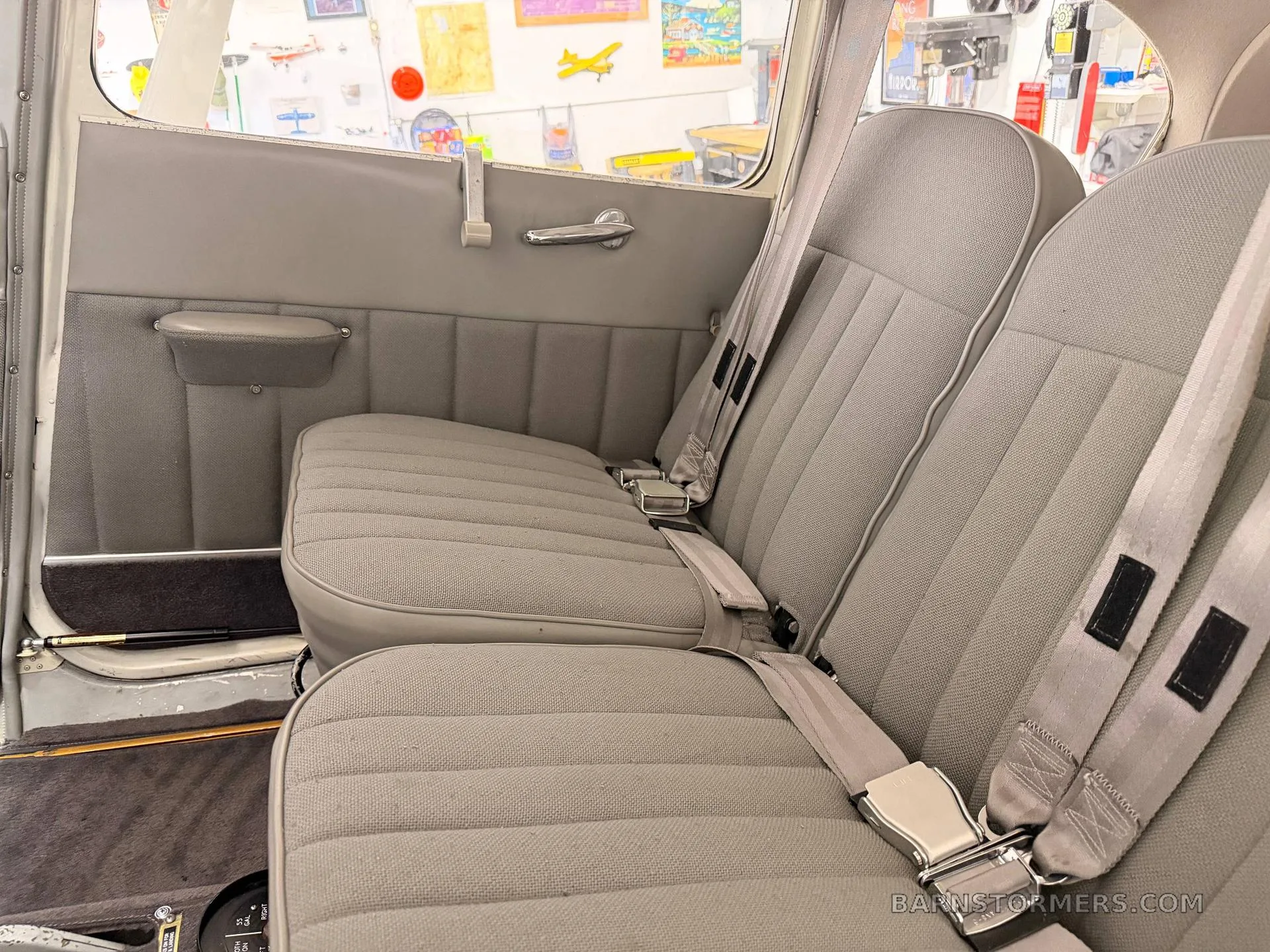 The gray fabric passenger seats in the cabin of a small aircraft, with seatbelts visible.