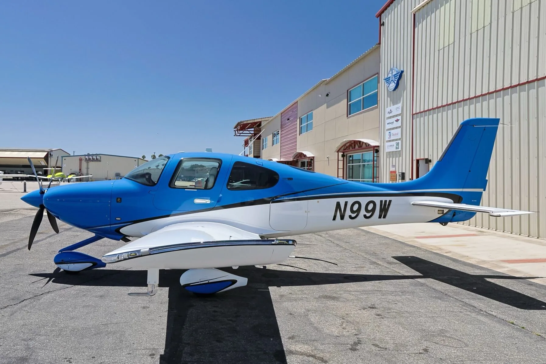 A blue and white Cirrus SR22 aircraft (N99W) parked on an airfield.
