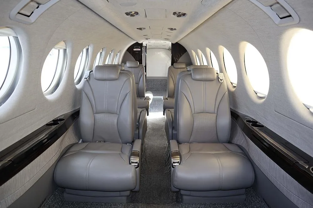 The interior cabin of the aircraft with four grey leather passenger seats facing each other.