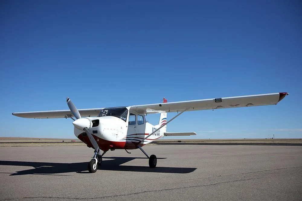 A white and red single-engine propeller aircraft, N731AX, parked on an airfield under a clear blue sky.
