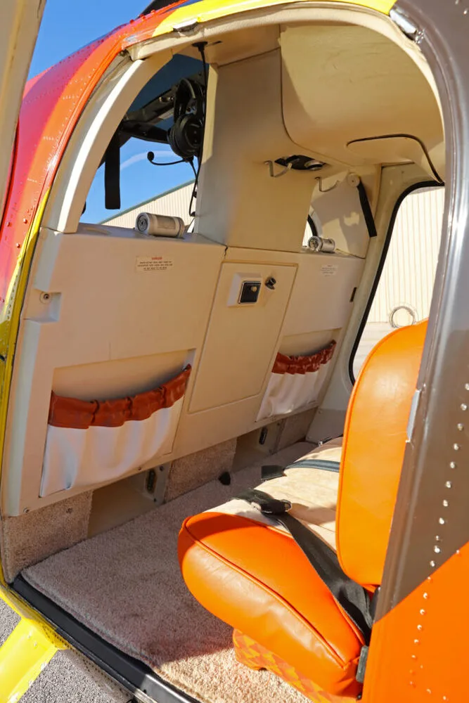 The beige and orange interior cabin of a helicopter, showing seats and side panels.