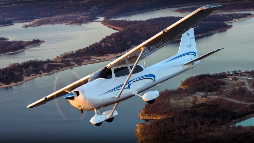 A Cessna Skyhawk flying over a lake.