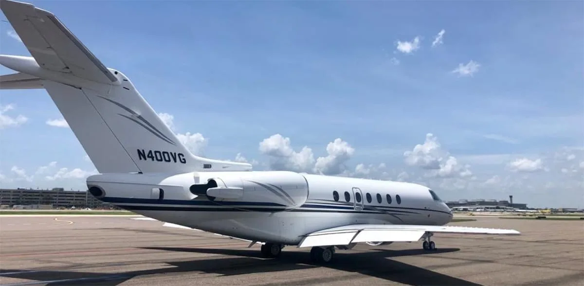 The rear view of the N400VG business jet, showing its white fuselage with dark blue and grey stripes on an airport tarmac.
