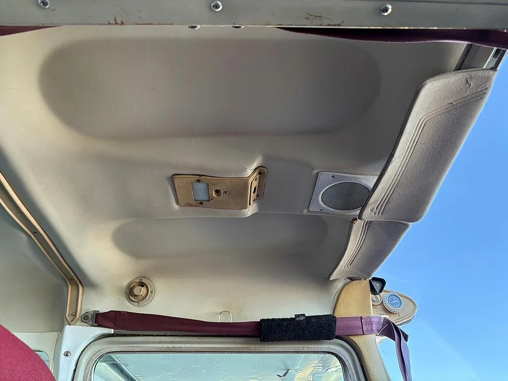 View of the aircraft cabin ceiling with a light fixture and speaker.