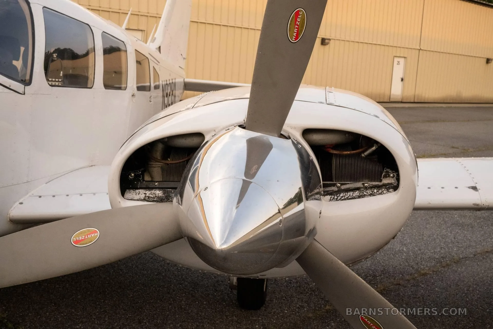 A close-up view of the right engine and propeller of a white twin-engine aircraft, showing the Hartzell propeller.