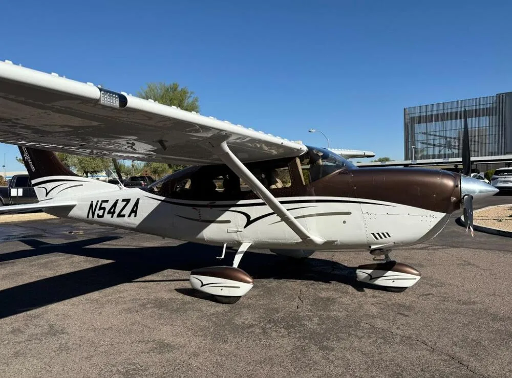 A side view of a brown and white Cessna 206 Stationair aircraft (N54ZA) parked on a tarmac.