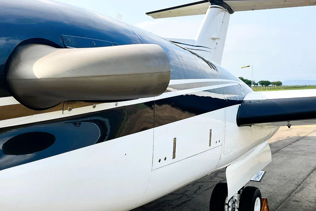 A close-up view of the white and black fuselage and engine nacelle of a Beechcraft King Air 250 aircraft.