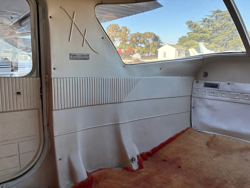 The rear cabin interior of a small aircraft with beige paneling and orange carpet.