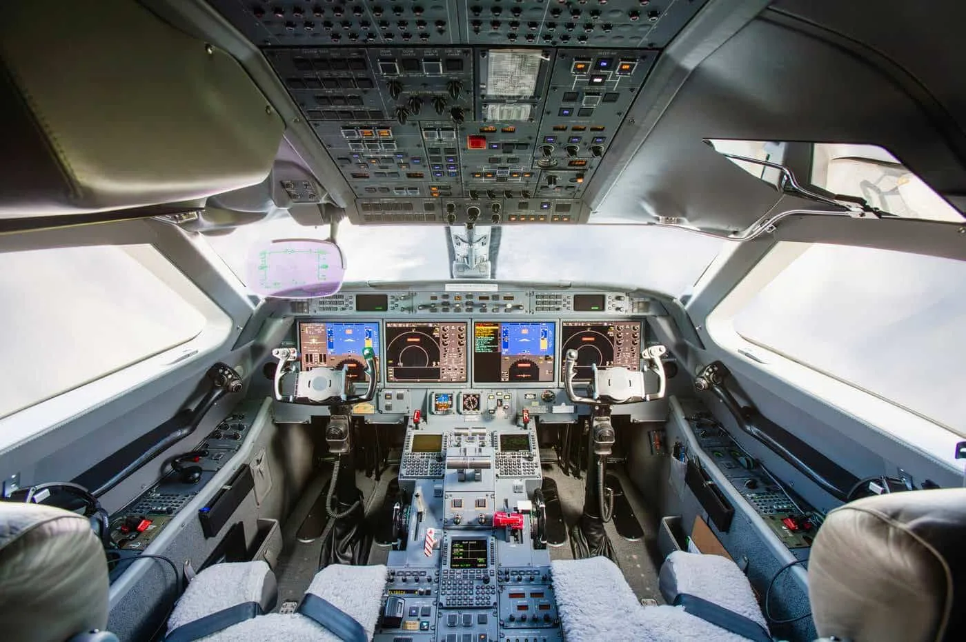 The modern cockpit of a business jet with multiple digital displays and control panels.