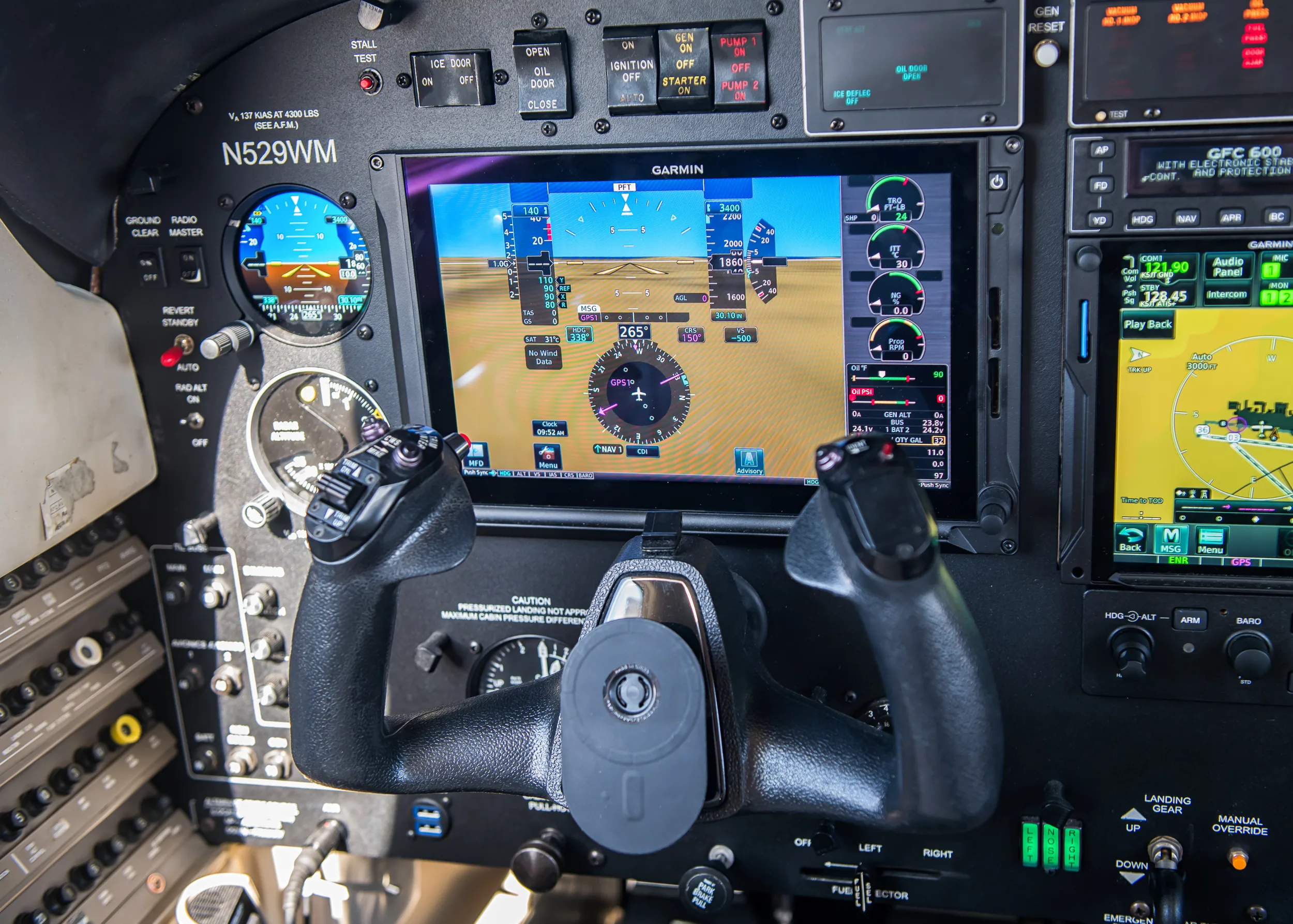 A close-up of the pilot's side of the N529WM cockpit, featuring a Garmin G1000 display showing flight information and a control yoke.