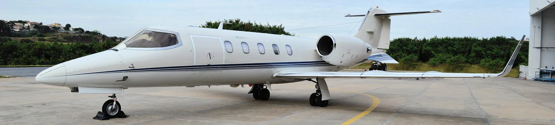 A Learjet aircraft is parked on the tarmac in front of a hangar.