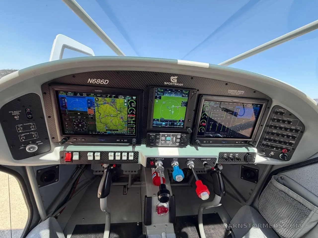 The cockpit of a Sportsman aircraft features a modern glass panel with three Garmin displays and various controls.