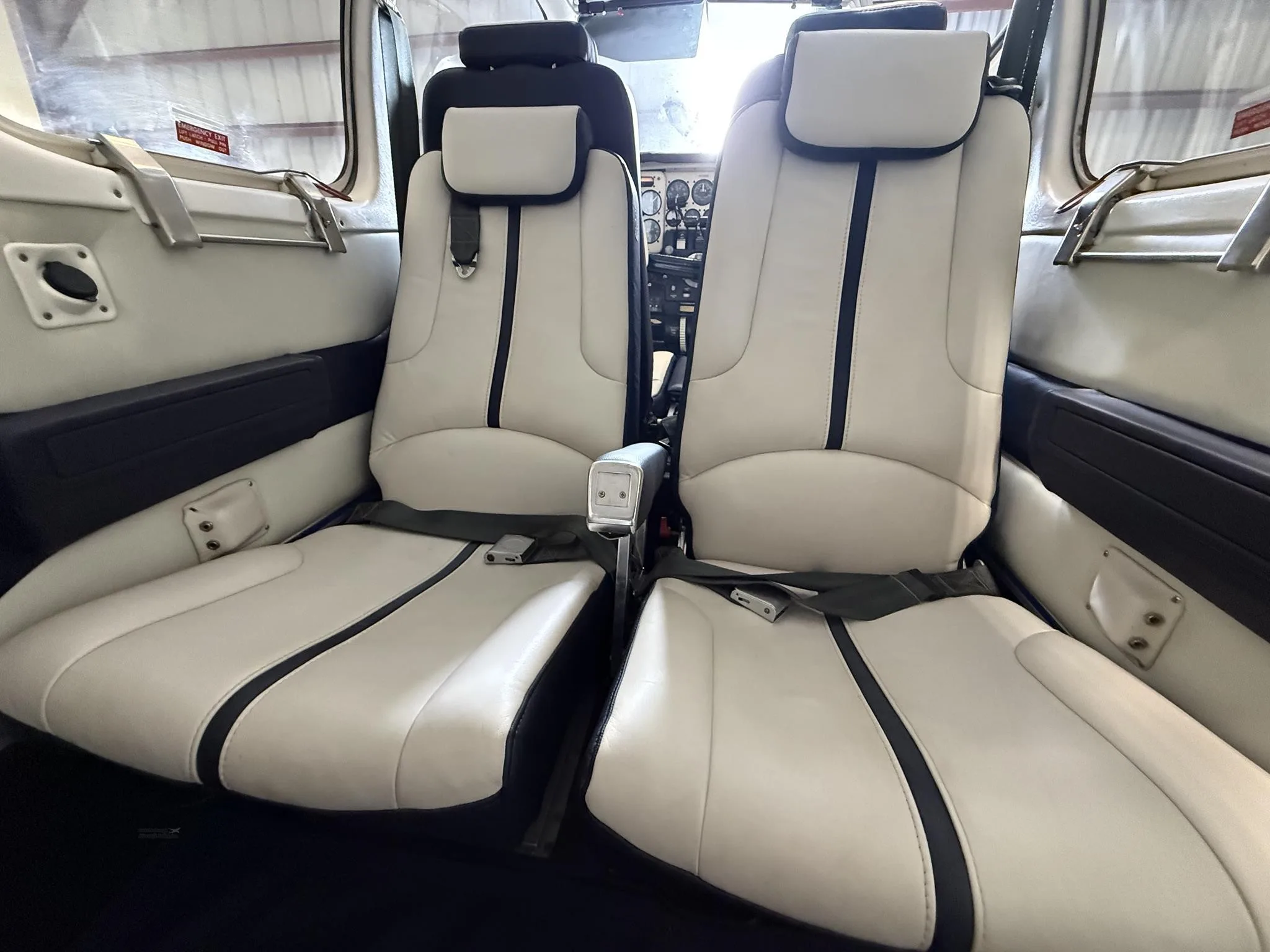 Close-up of the two front passenger seats in the aircraft's cabin, upholstered in white and blue leather.