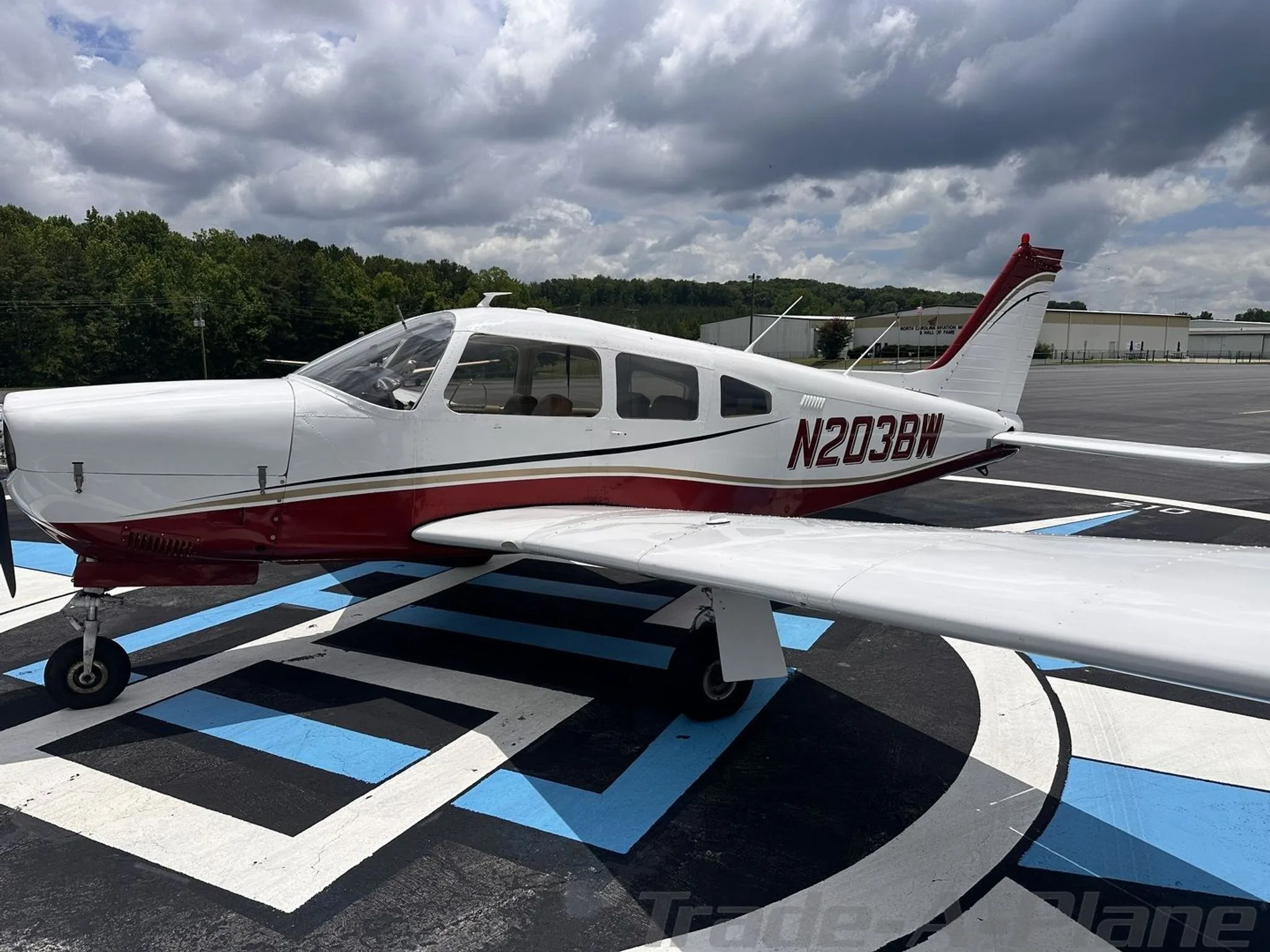 A side profile view of the white and red aircraft N203BW parked on an airport tarmac.