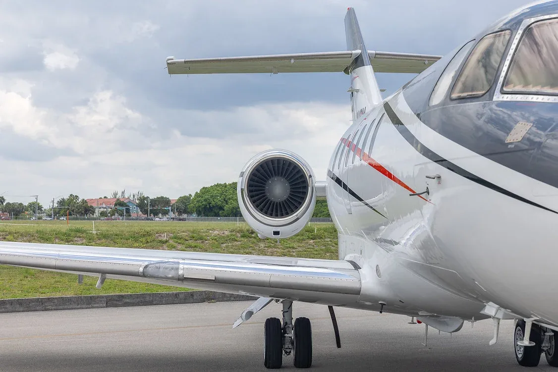 A close-up view of the engine and wing of a white business jet, registration N432SM, on an airfield.