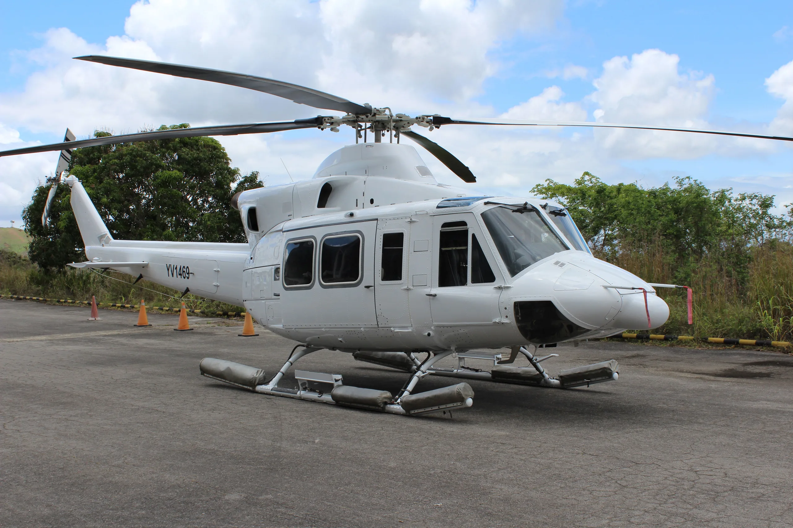A white Bell 412 helicopter with registration YJ-H8 parked on an asphalt surface.